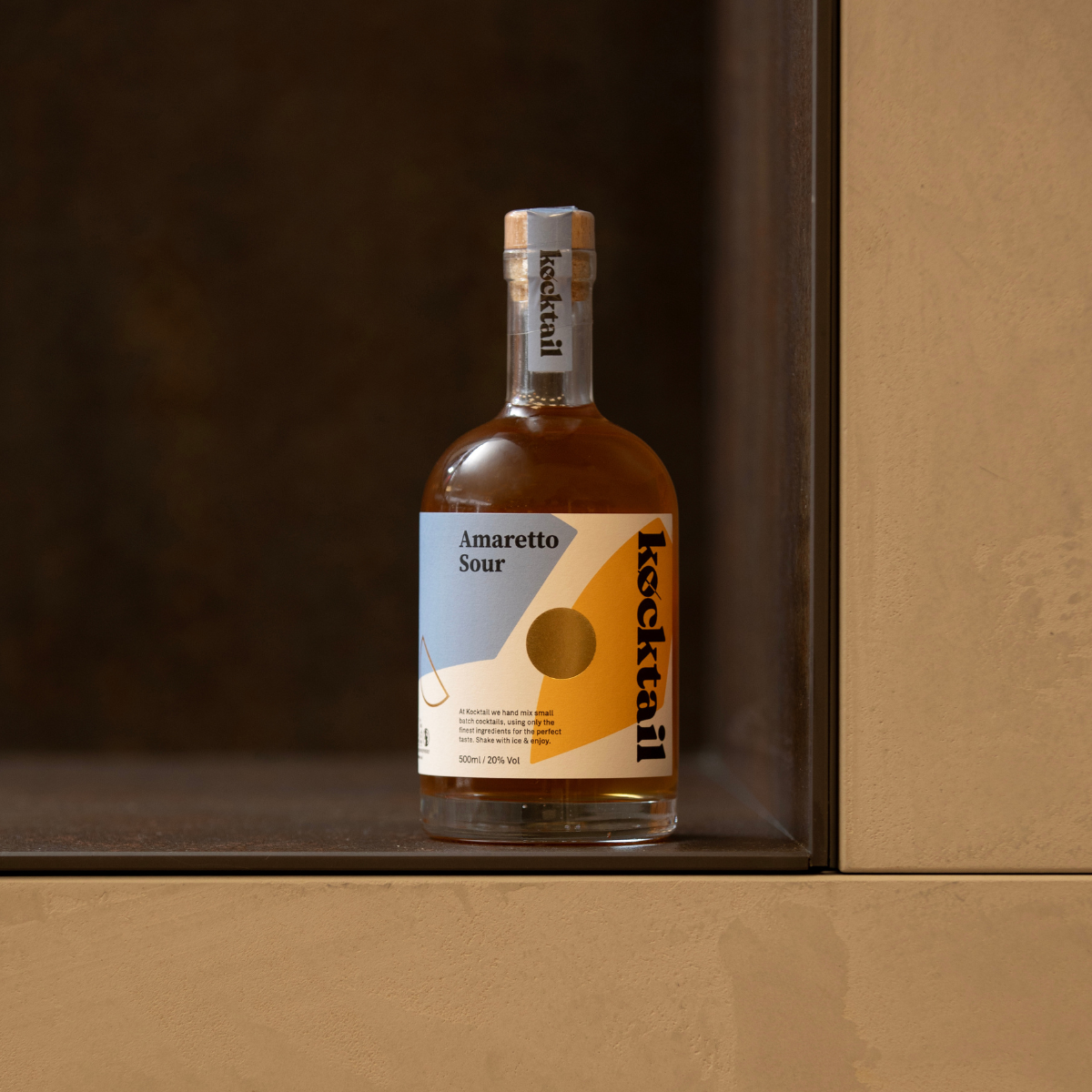 Bottle of Kocktail Amaretto Sour displayed on a wooden surface, highlighting creamy foam and nutty almond liqueur blend