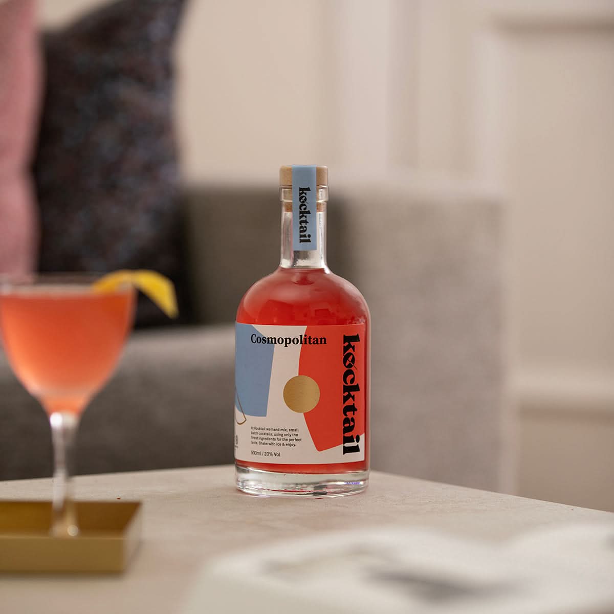 Kocktail Cosmopolitan 50cl bottle displayed beside a poured cocktail in a martini glass, highlighting vibrant colour and elegant presentation.