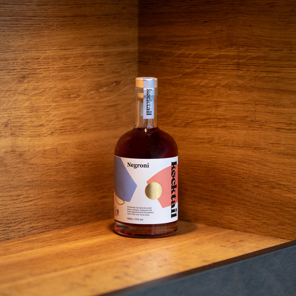 Kocktail Negroni 50cl bottle displayed on a shelf, showcasing elegant label design and rich red spirit